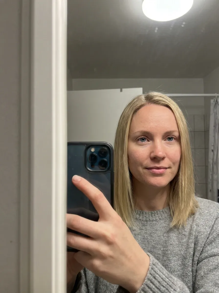 Original selfie input — blond woman in a light gray top, mirror selfie